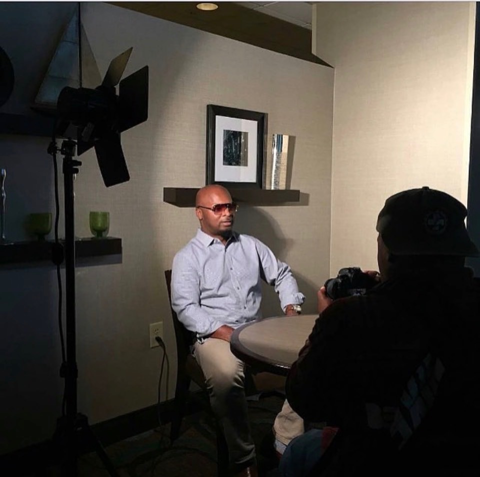 A photographer filming a seated portrait subject in a softly lit interior