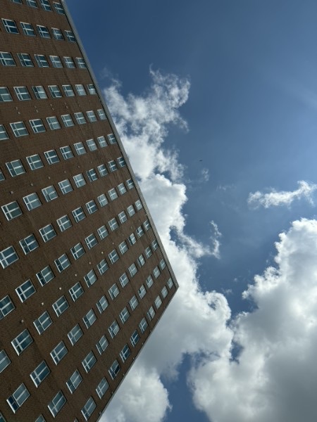 Upward architectural view of a brick building against blue sky and clouds