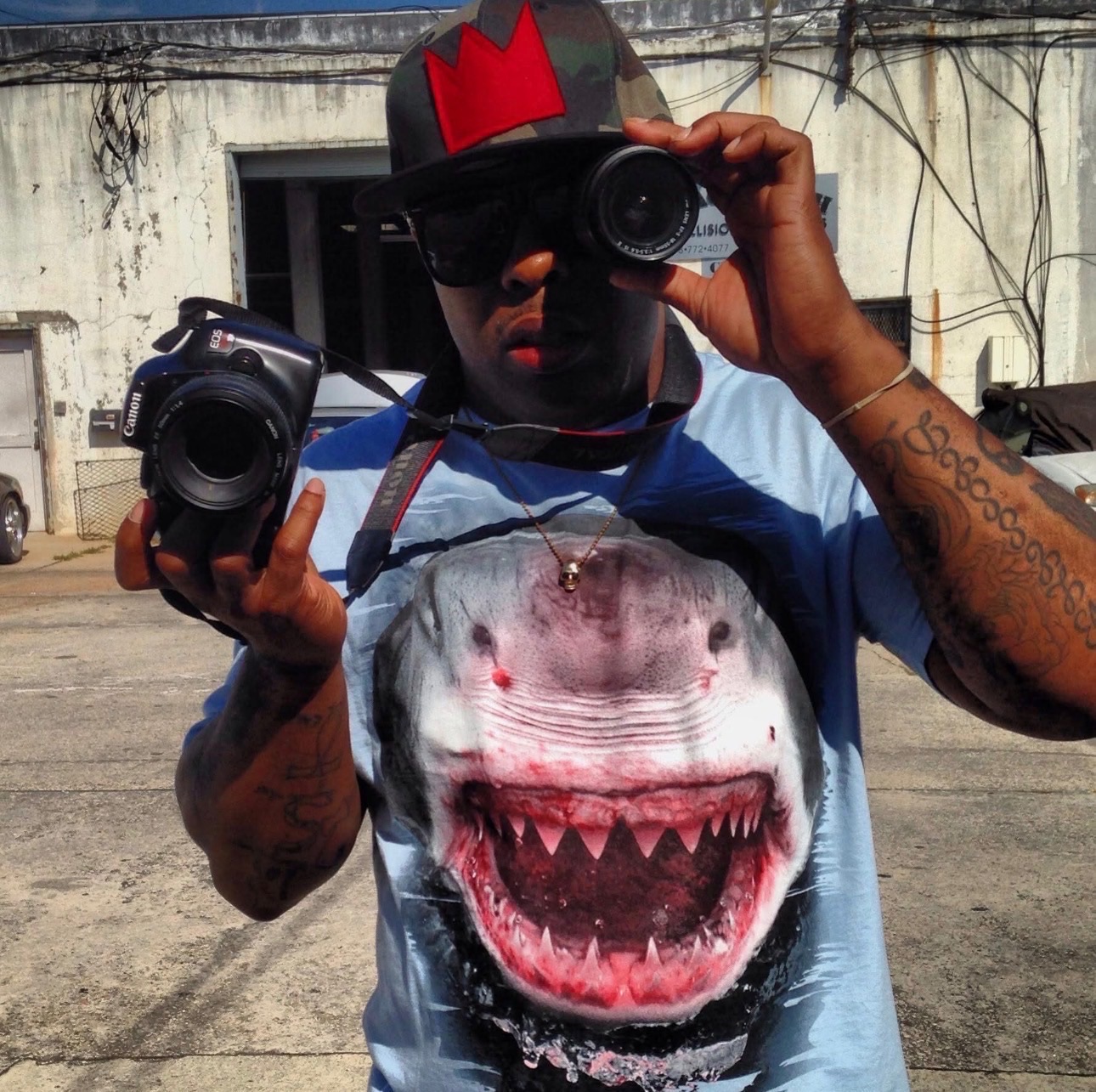 A photographer looking through a small camera while holding a second camera